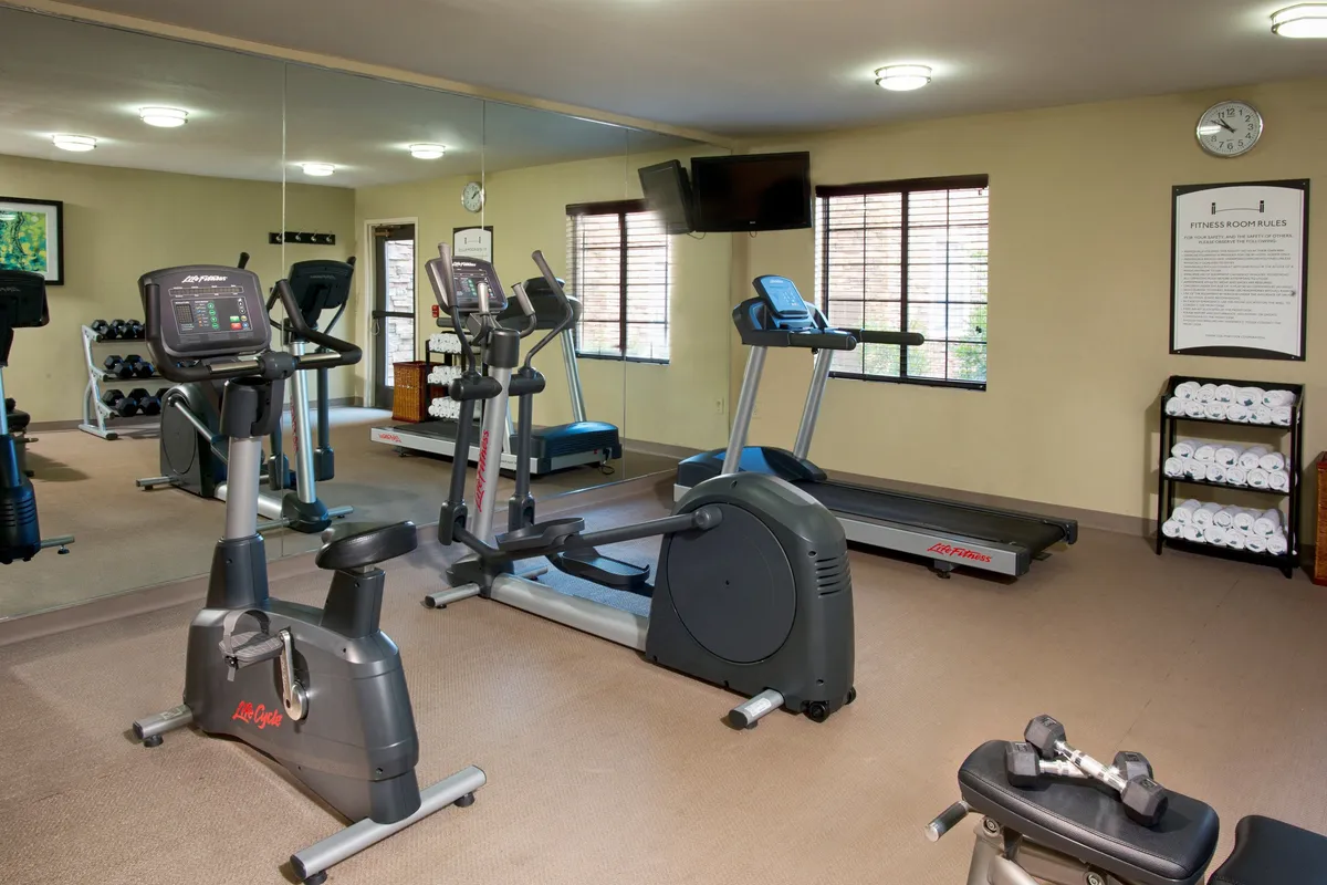 A bright, energizing fitness center filled with modern exercise equipment, a mirrored wall, and towels ready for guests. The space is designed to motivate and support both individual and group workouts, promoting a sense of well-being and community.