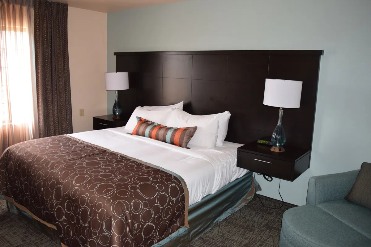 This image features a living space with a plush sofa, decorative pillows, a comfortable bed, nightstands, and a lamp. The cozy layout is enhanced by personalized touches and soft lighting, creating a relaxing and welcoming ambiance. The presence of both seating and sleeping areas highlights the multifunctionality of the condo's interior.
